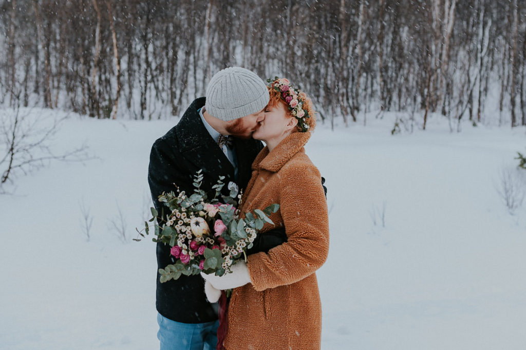 Bride and groom kissing on the day of their intimate winter wedding