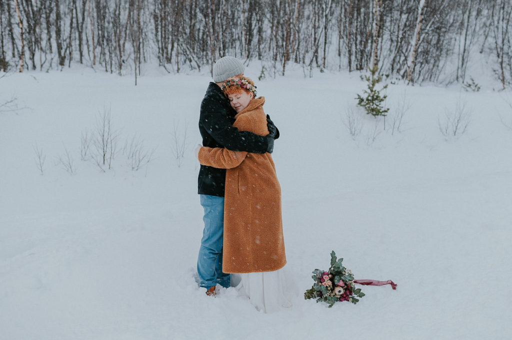 Groom is hugging his bride to warm her up on a cold winter day of their wedding in Norway