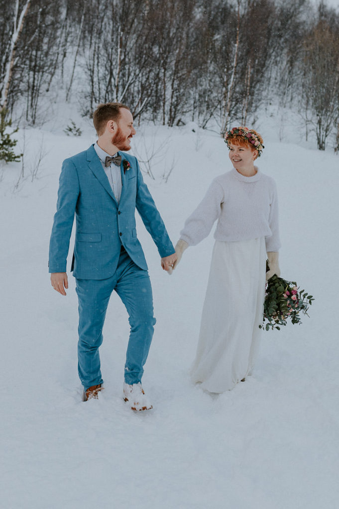 Bridal couple eloping in Norway in winter time  - walking aroung in front of a forest landscape