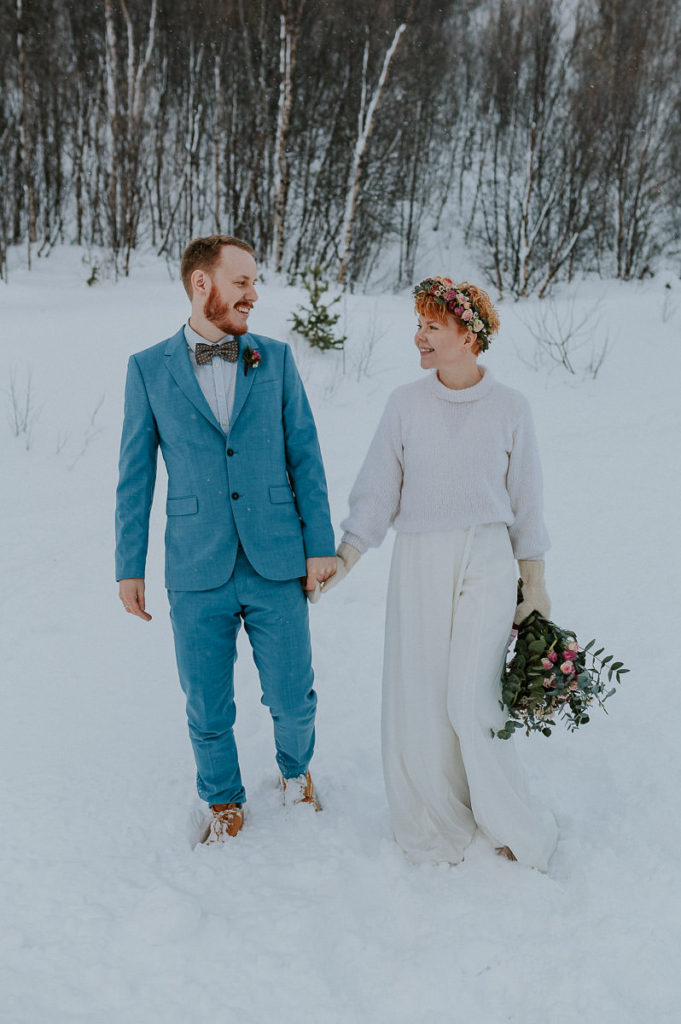 Bridal couple eloping in Alta Norway in winter time  - walking aroung in front of a forest landscape