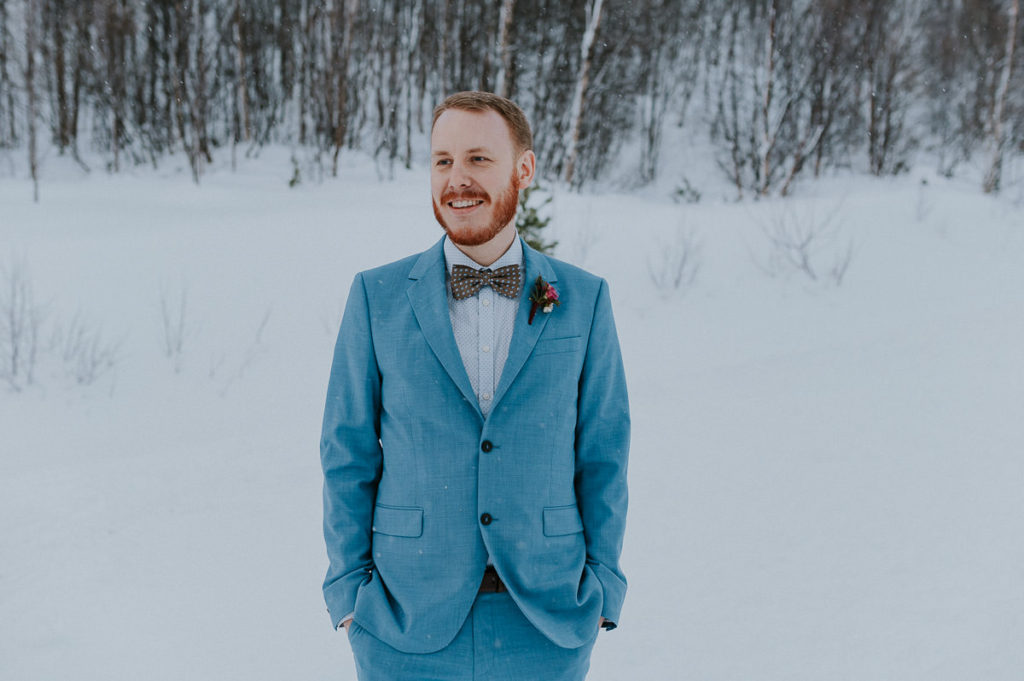 Groom in a blue suit outdoors on the day of his winter elopement in Norway