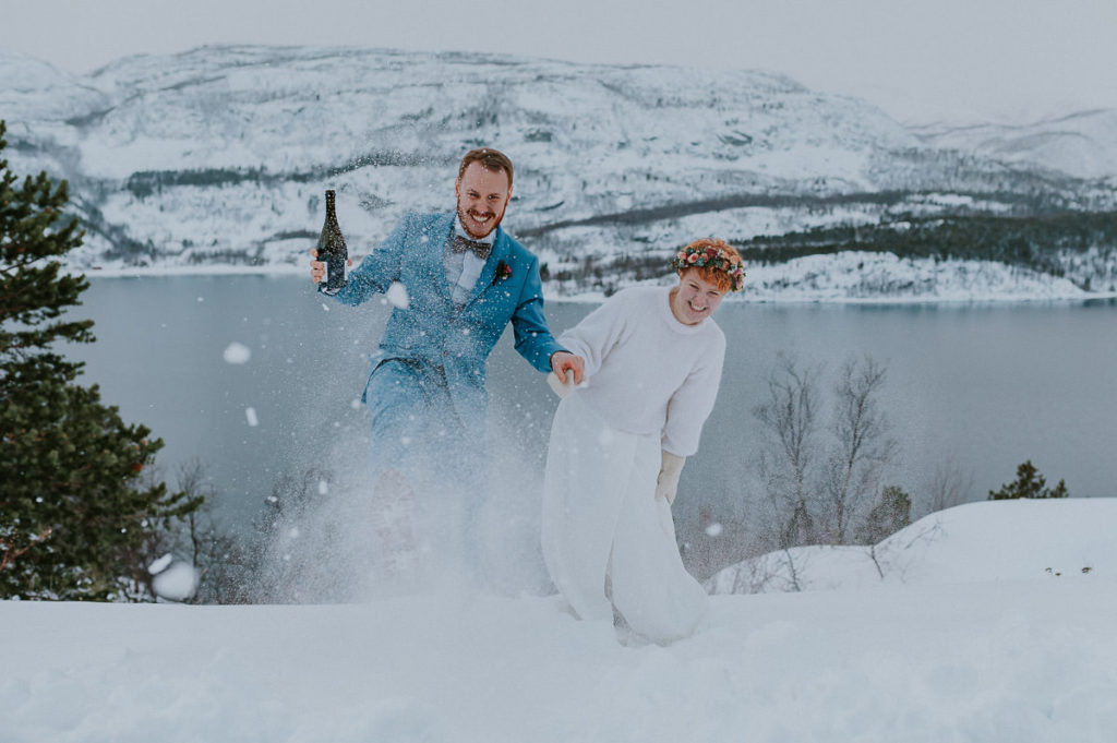 Bride and groom playing with the snow on the day of their winter elopement in Norway