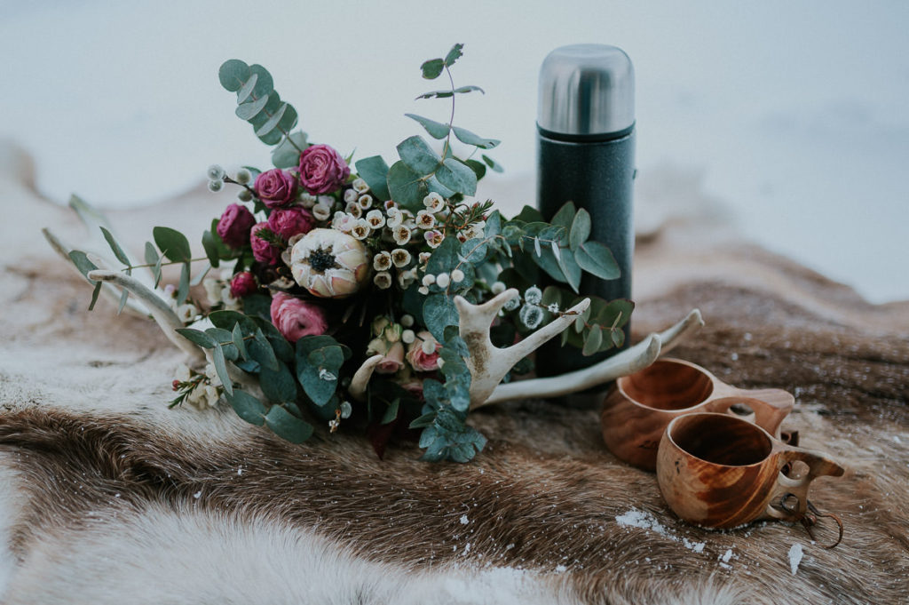 Beautiful winter wedding bouquet decorated with nordic and sami theme in mind - antlers and wooden coffe cups 