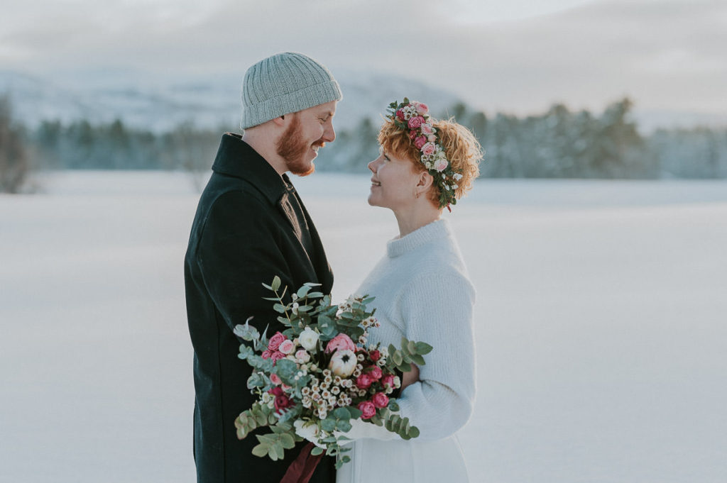 Beautiful bride and groom portraint in front of a winter landscape with mountains and forest on the day of their winter elopement in Norway