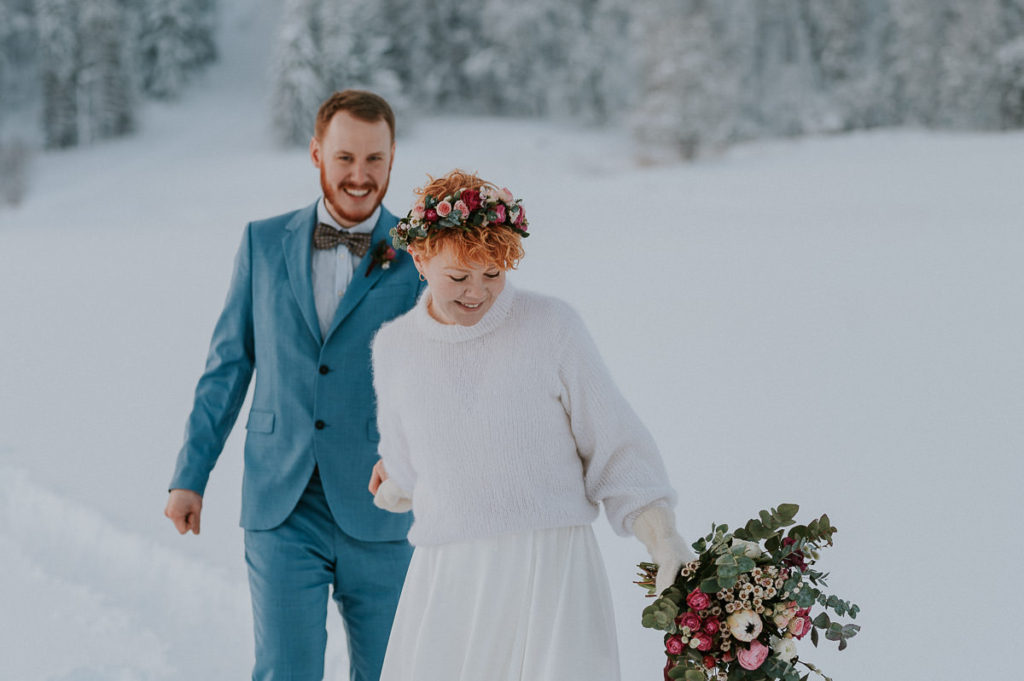 Bride and groom walking to their winter elopement location - snowshoeing through the snow in Northern Norway