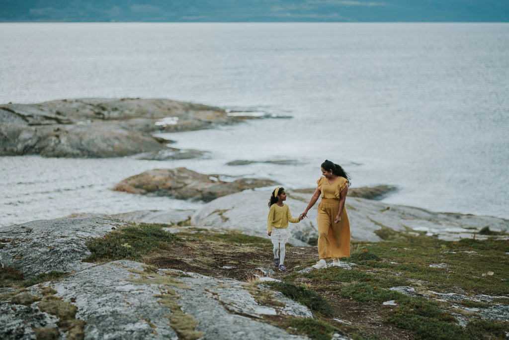 Mor og datter går på bergene langs havet i Alta mens de holder hverandres hender