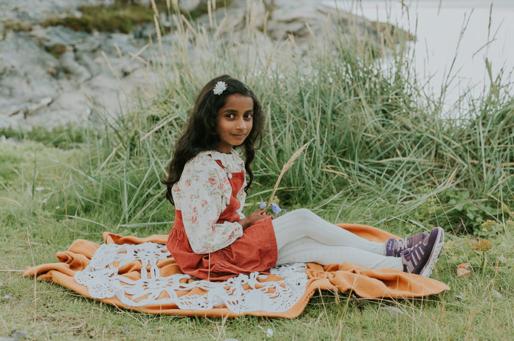 Portrett av en 7 år gammel jente som sitter ved havet i Alta
