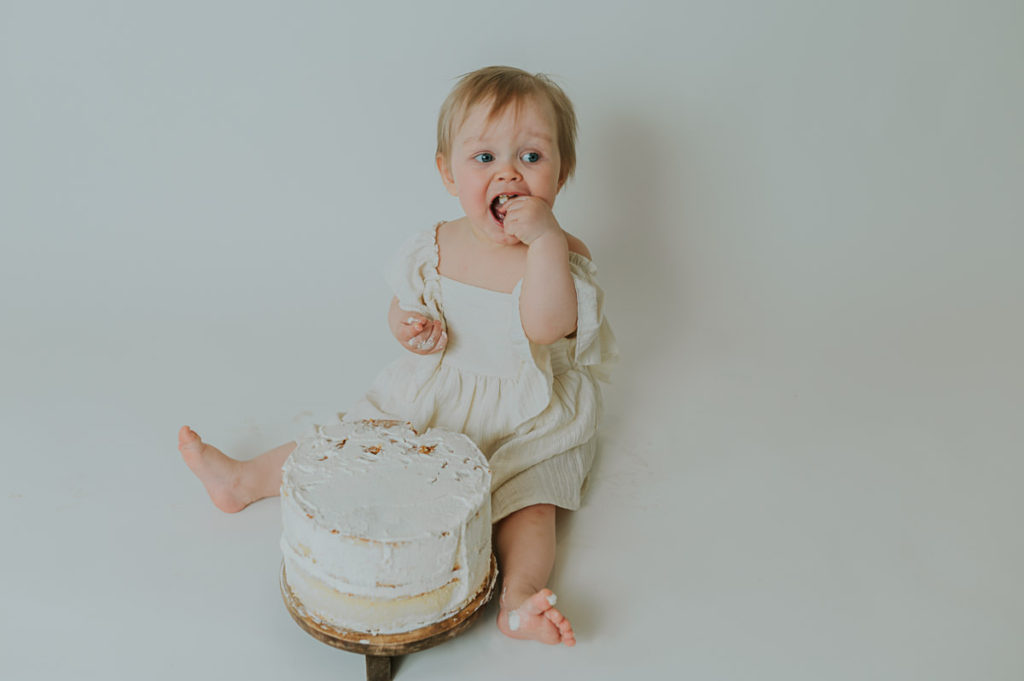 Ettårsfotografering cake smash for en baby jente - babyen smaker på kaken sin