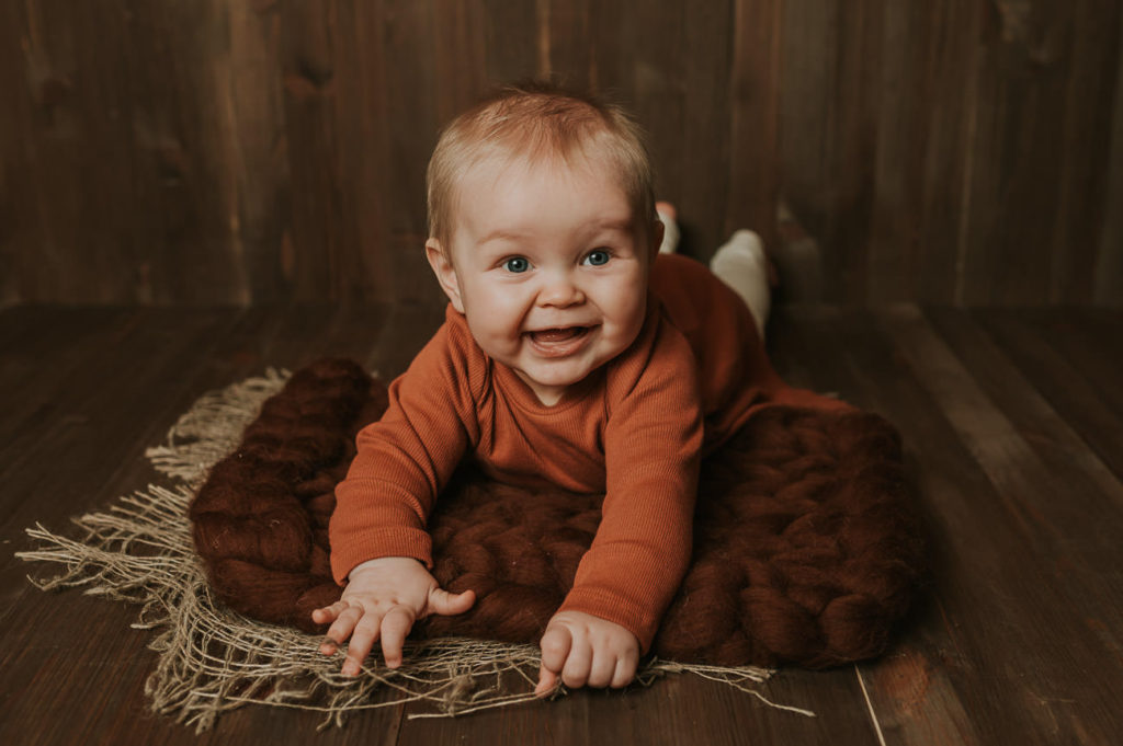 Fotoprosjekt ett år i bilder - babyfotografering fra måned til måned - en søt babyjente ligger på magen og smiler 