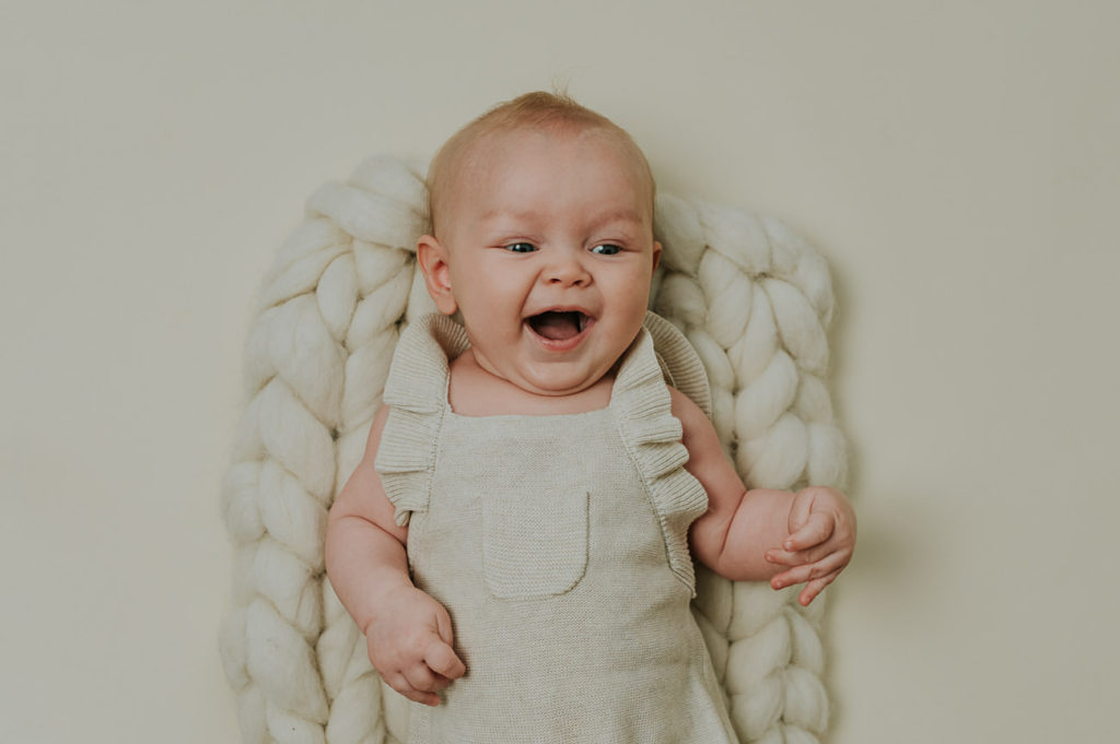 Søt baby jente på 4 måneder smiler bredt på milepælfotografering i Alta i fotostudio TS Foto Design