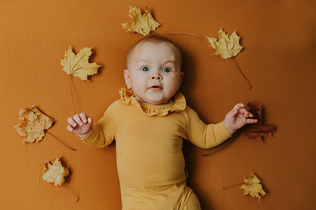 Søt baby jente på 5 måneder på gul fotobakgrunn med høst-tema på milepælfotografering i Alta i fotostudio TS Foto Design