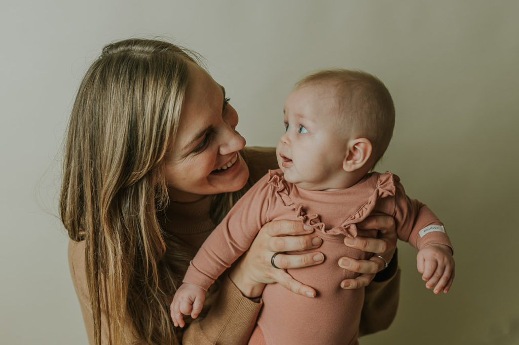 Ett år i bilder - babyfotografering fra måned til måned - bilde av mor og 5 måneder gammel baby i armene i lyse studio omgivelser