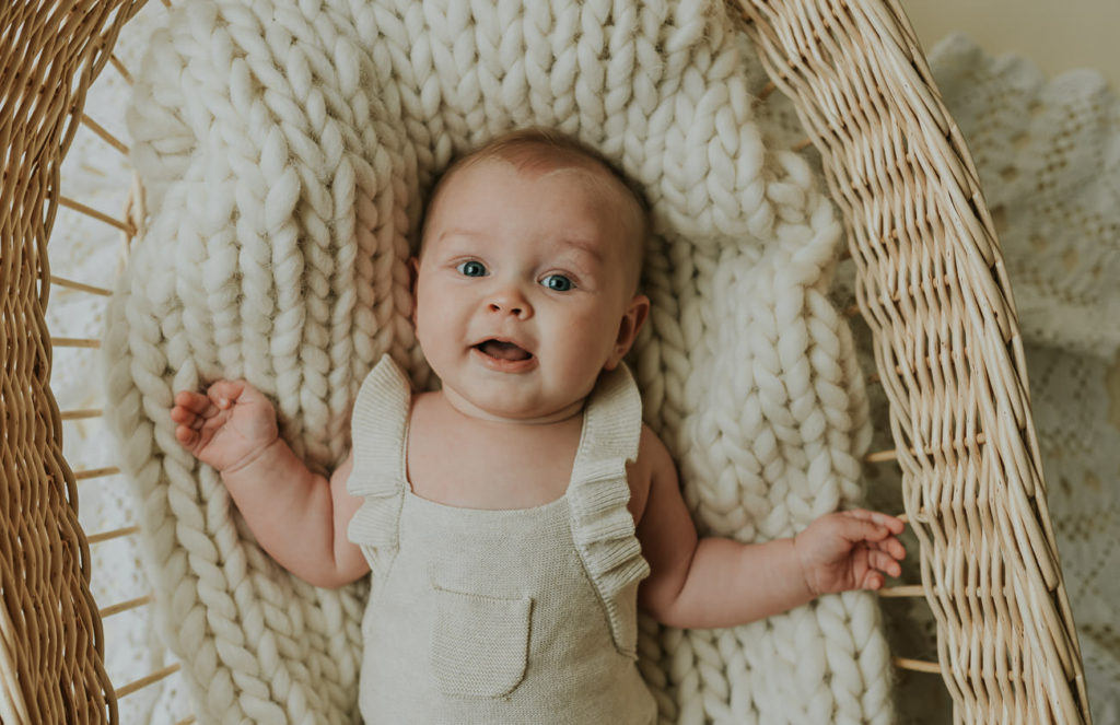 Søt baby jente på 5 måneder ligger i en baby kurv på milepælfotografering i Alta i fotostudio TS Foto Design