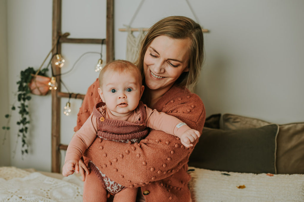 Ett år i bilder - babyfotografering fra måned til måned - bilde av mor og 6 måneder gammel baby i armene i lyse studio omgivelser