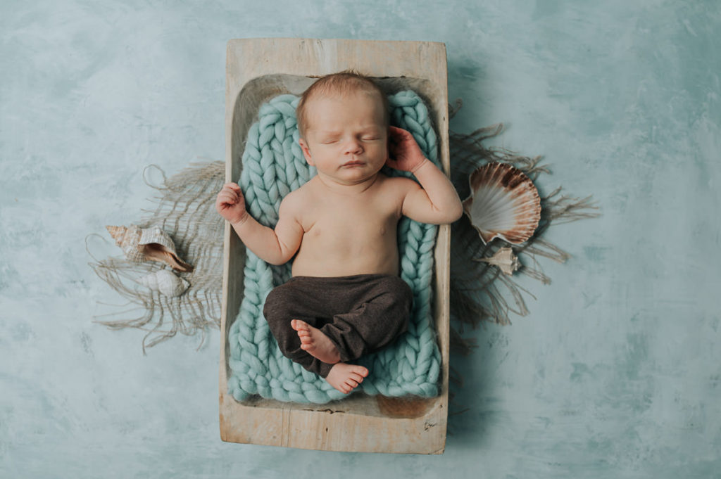Cute baby in a trench on a blue mintgreen backdrop - sea, beach and maritime newborn photoshoot theme