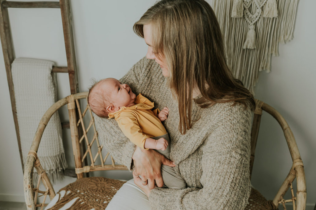 Ett år i bilder - babyfotografering fra måned til måned - bilde av mor og 1 måned gammel baby i armene i lyse studio omgivelser