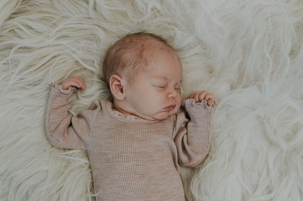 Skjønn baby jente sover på hvit sauskinn på nyfødtfotografering i Alta hos nyfødtfotograf TS Foto Design
