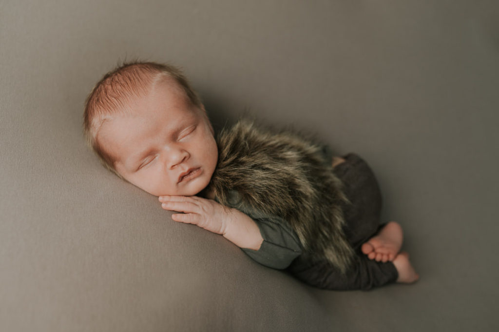 Beautiful newborn baby sleeping on his tummy on a beige backdrop in photo studio in Norway for his newborn session - viking theme newborn session