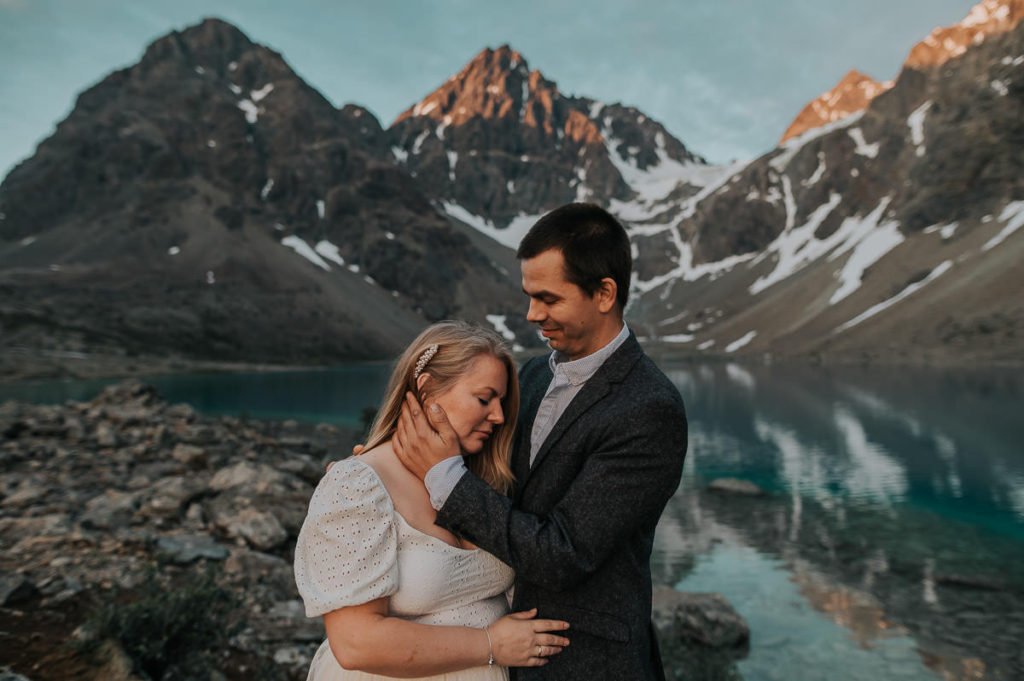 Bride and groom hugging each other among beautiful mountains and lake landscape