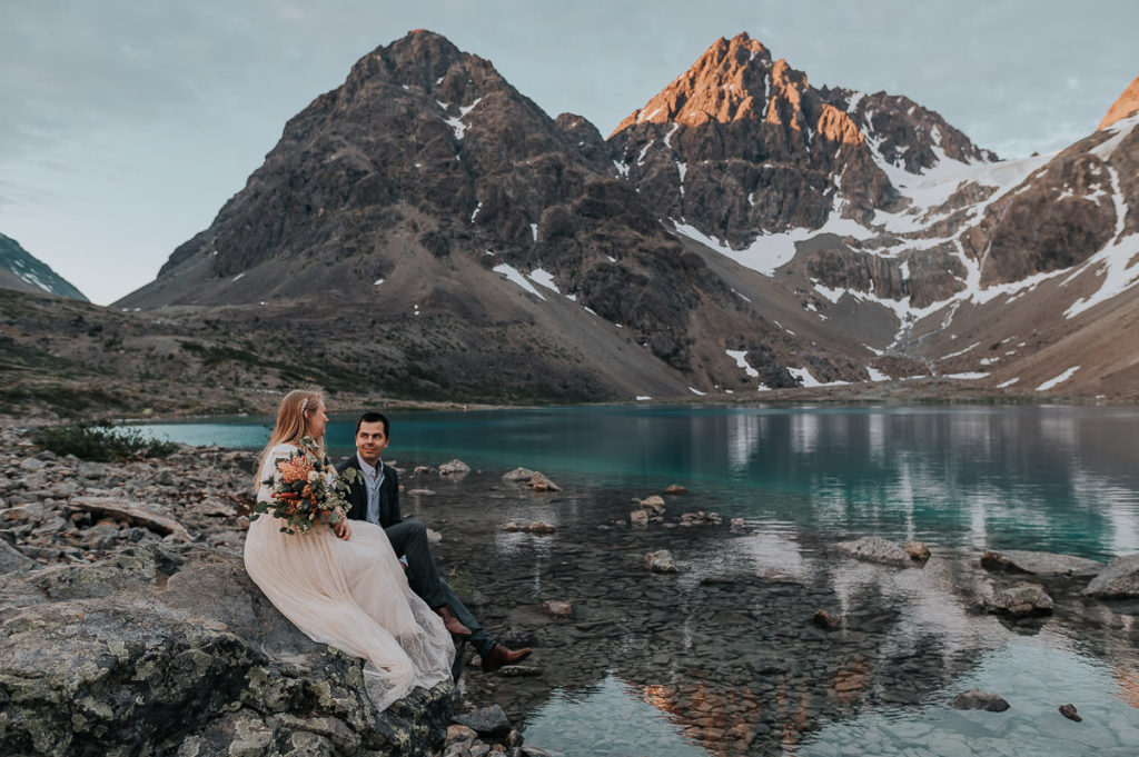 Bride and groom sitting near a clacial lake in Lyngen Alps in Norway