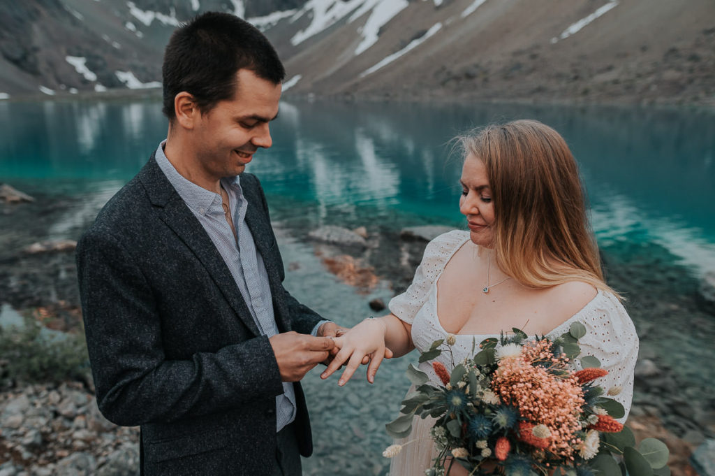 Bride and groom exchanging rings among beautiful landscape of Lyngen Alps on their pre-wedding photo session