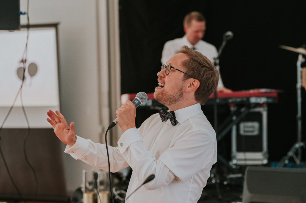 En av vennene til brudeparet synger en sang på bryllupsfesten i Kvenvikmoen i Alta