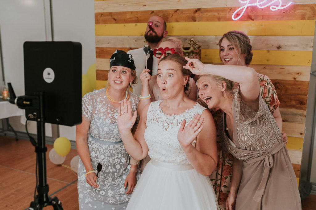 Brudeparet laget gult fotovegg og tar selfie med masse fotoprops på et festlig og fargerikt bryllup i Alta
