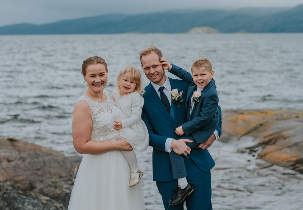 Familiebilde med brudepar og to barn foran havet i Alta