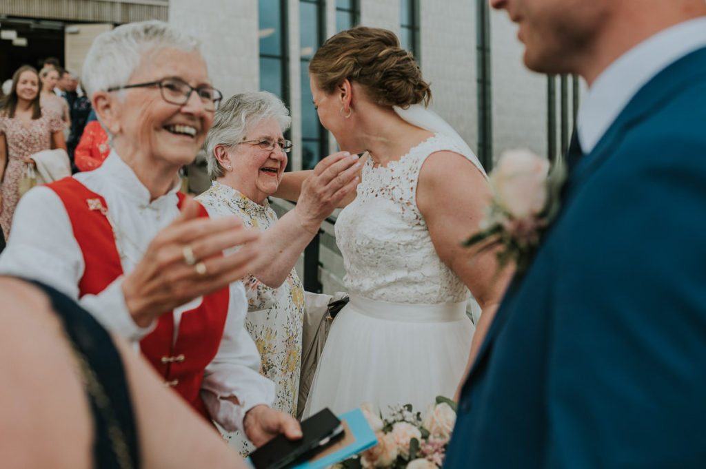Brudeparet får en klem av bestemor utenfor kirka
