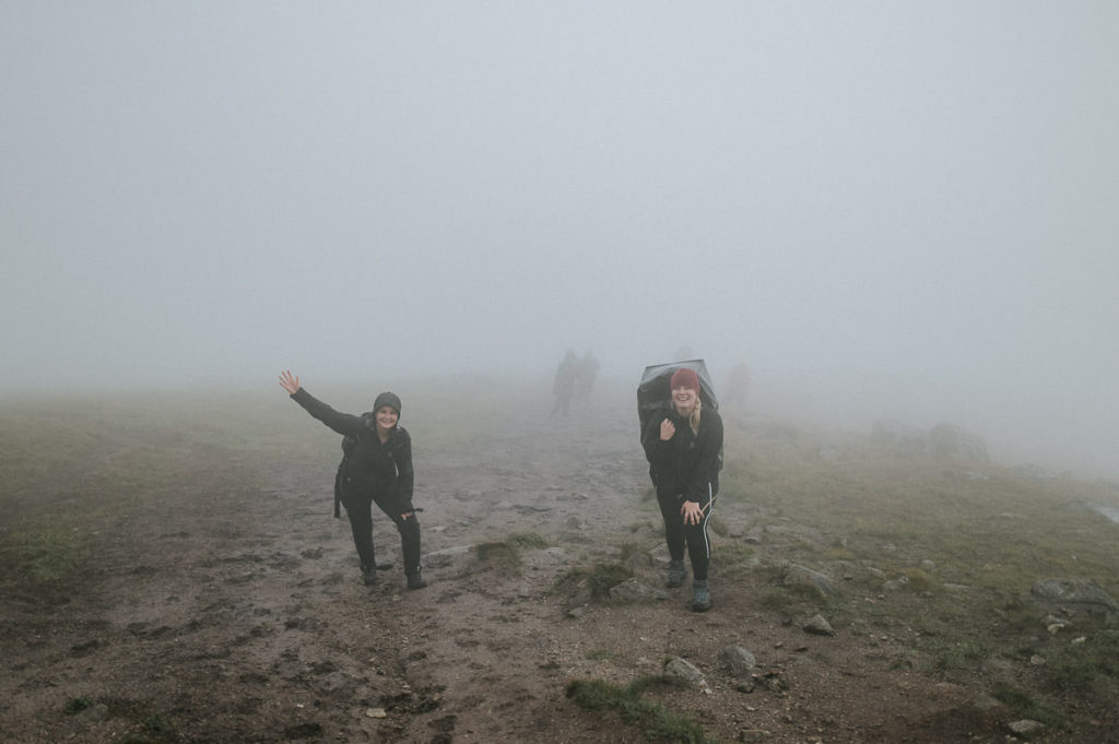 Bride and groom and their guests hiking up the hills in the fog and rain to celebrate their adventure wedding in Lofoten