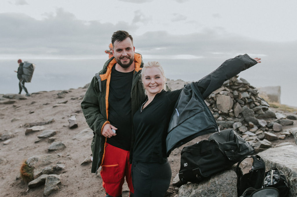 Bride and groom hiked up the hills in the fog and rain to celebrate their adventure wedding in Lofoten and now cheering at the top while the sky is clearing