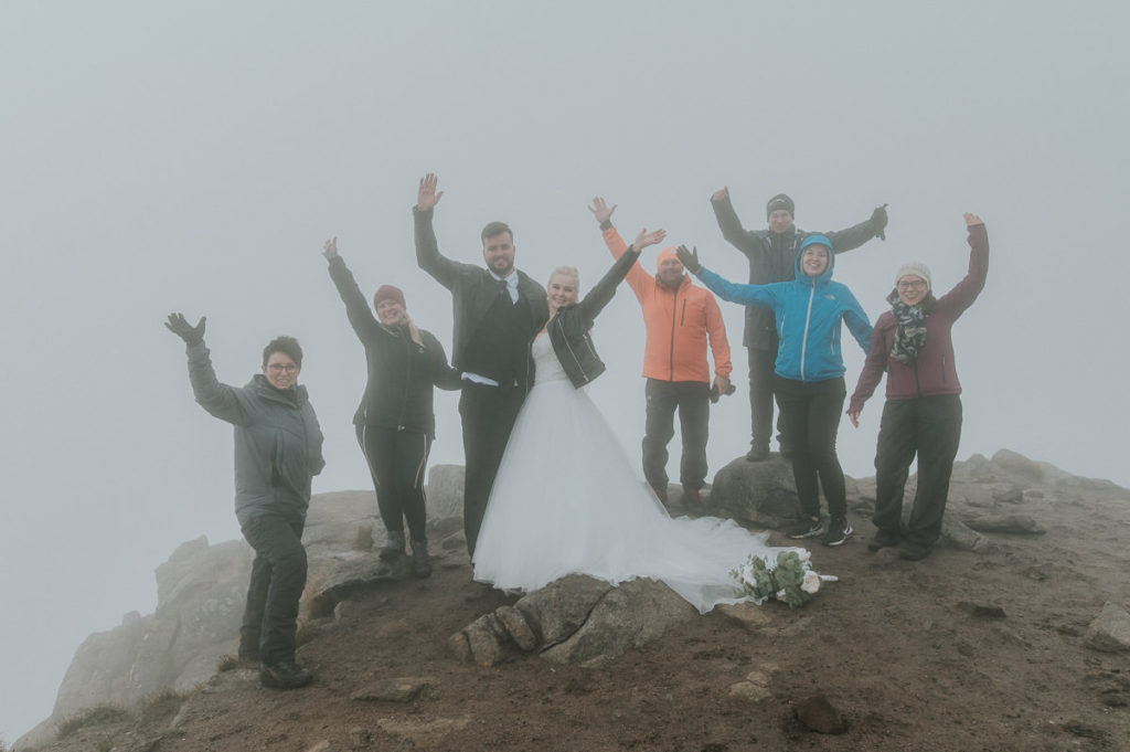 Bride and groom and a small group of their guests are cheering and celebrating an intimate adventure wedding in the mountains of Lofoten islands 