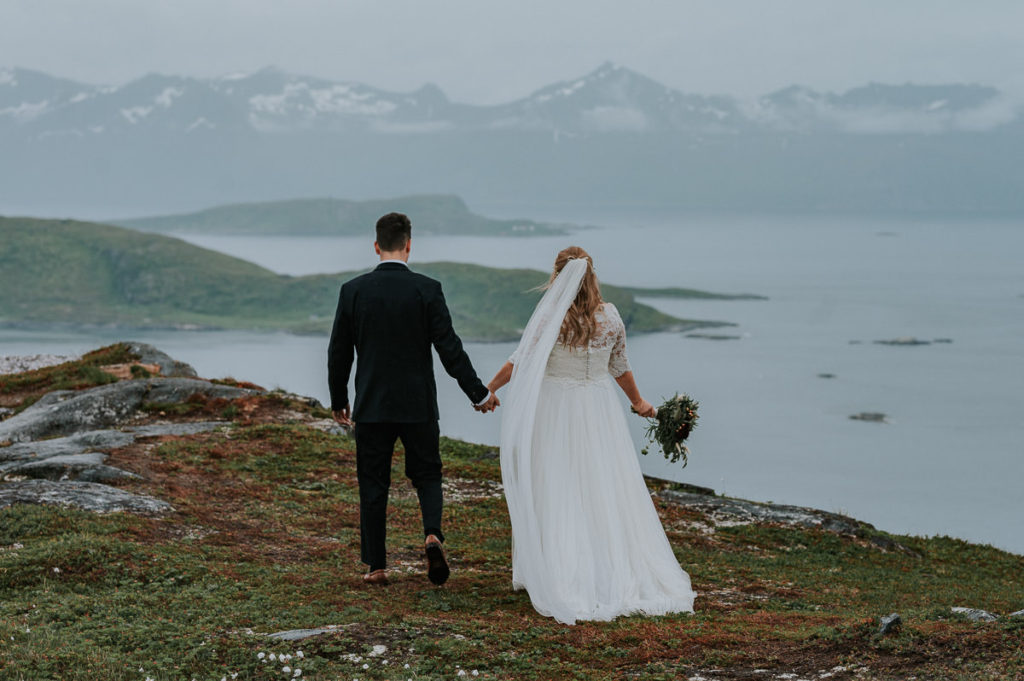 Bride and groom walking in the mountains of Tromsø on their wedding day