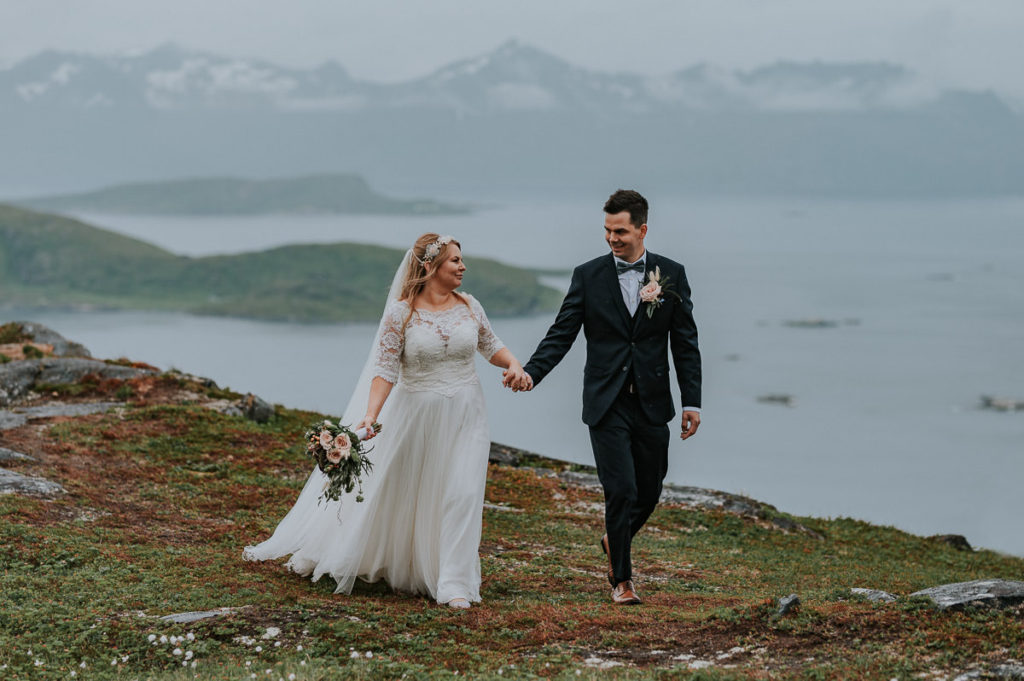 Bride and groom walking in the mountains of Tromsø on their wedding day at Sommarøy