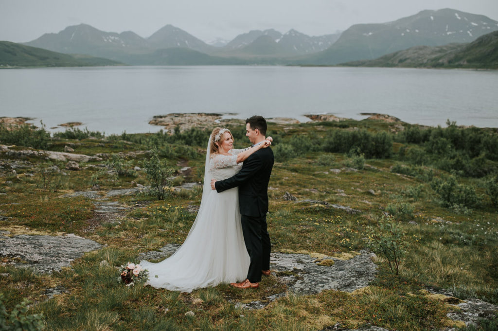 Bride and groom kissing in front of beaufitul view with the  sea and mountains in Sommarøy - captured by Tromsø wedding photographer TS Foto Design