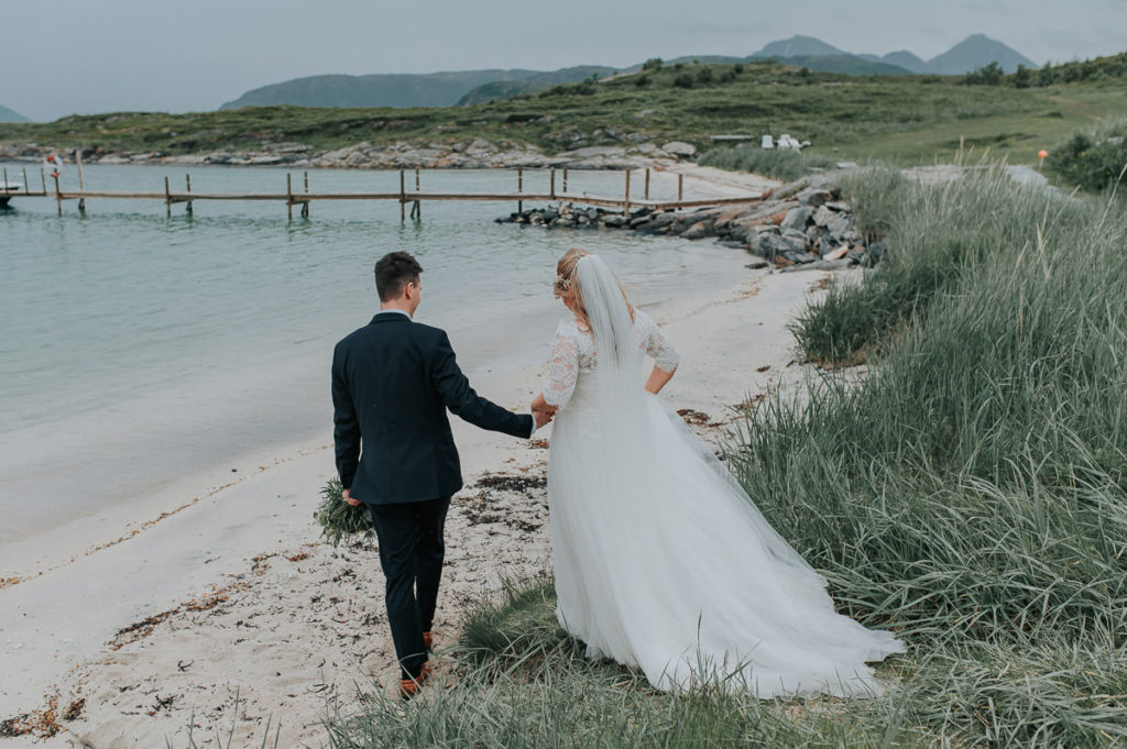 Bride and groom walking towards a beautiful beach in Sommarøy in Tromsø  on their wedding day