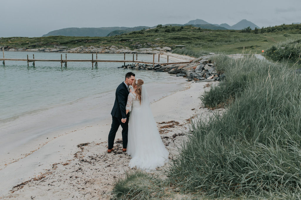 Bride and groom kissing in front of beaufitul view with the  sea and mountains in Sommarøy - captured by Tromsø wedding photographer TS Foto Design