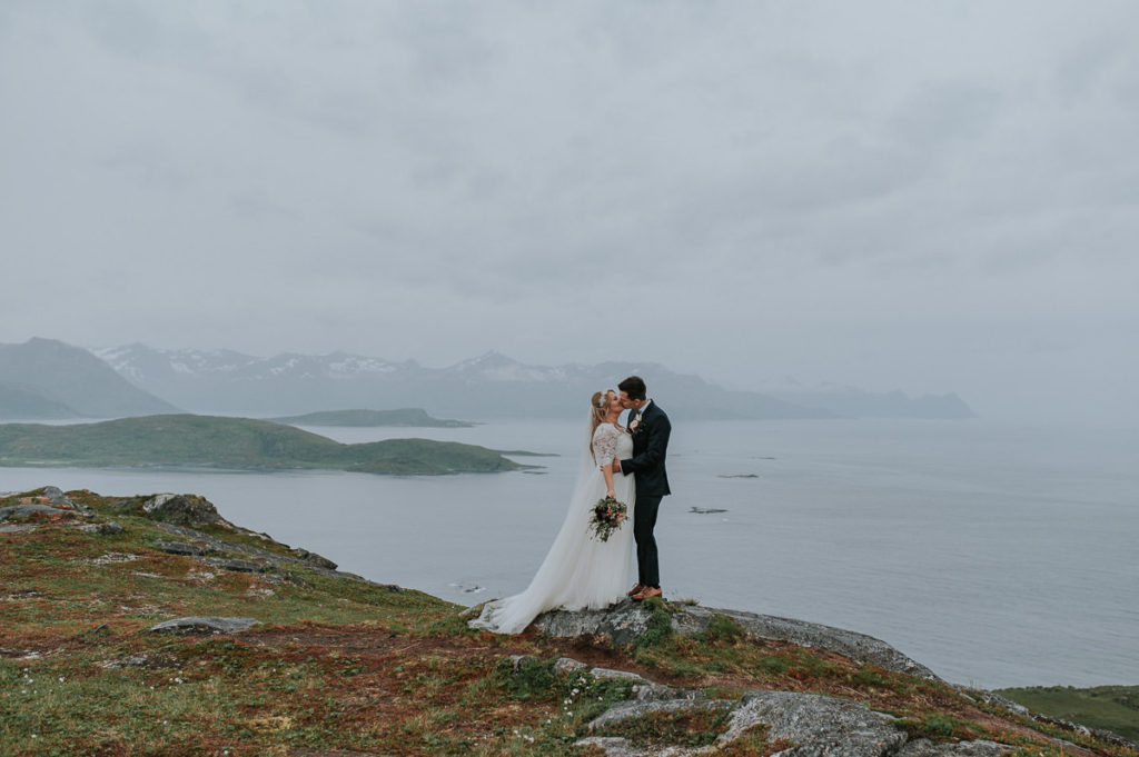 Bride and groom kissing in the mountains of Tromsø on their wedding day at Sommarøy by photographer TS Foto Design