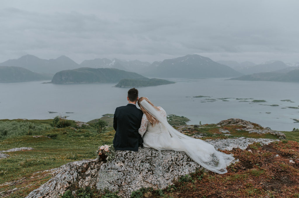 Bride and groom sitting on rocks on a mountaintop in Sommarøy Tromsø on their wedding day