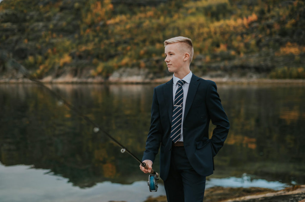 Portrett av en konfirmant med en fiskestang foran havet i Alta på en konfirmantfotografering 