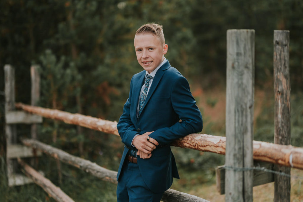 En konfirmant gutt ikledd dress på konfirmantfotografering i en skog i Alta 