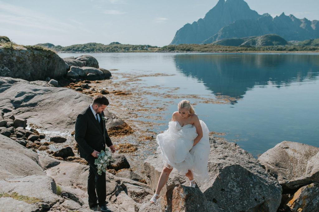 Bride and groom portraits near the sea and mountains on a sunny summer adventure wedding day in Lofoten 