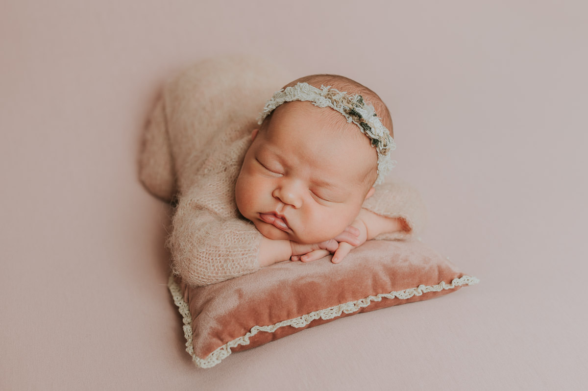 Baby jente med rosa klær på ligger på rosa bakgrunn og sover på nyfødtfoto i studio hos nyfødtfotograf TS Foto Design