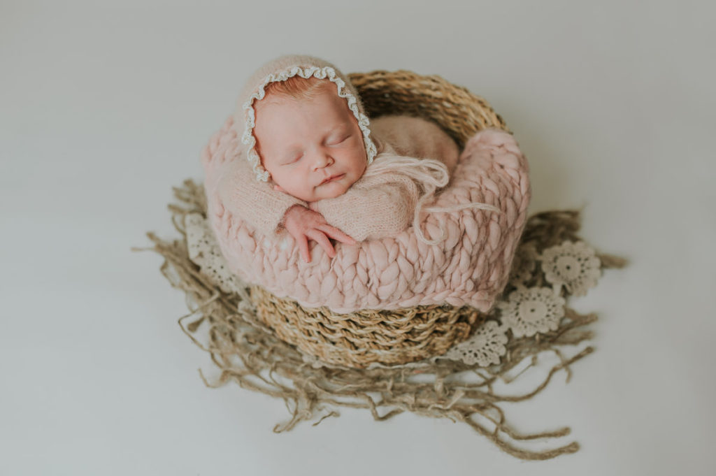 Baby jente med rosa klær på ligger i en kurv og sover på nyfødtfoto i studio i Alta hos nyfødtfotograf TS Foto Design
