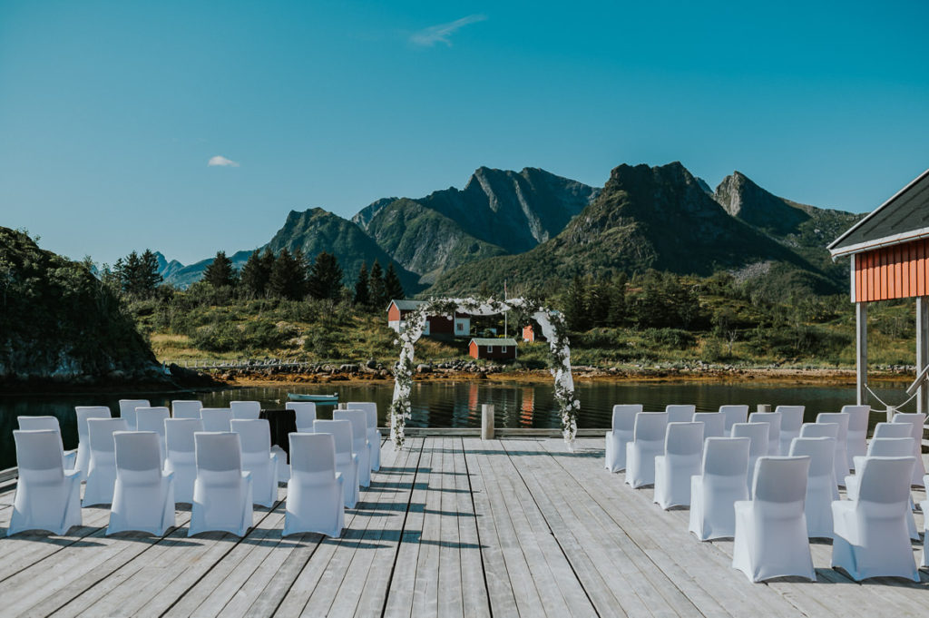 Floral arch decorated with white flowers in front of stunning mountains of Lofoten - everything is ready for an outdoor wedding ceremony in Nyvågar rorbu hotel