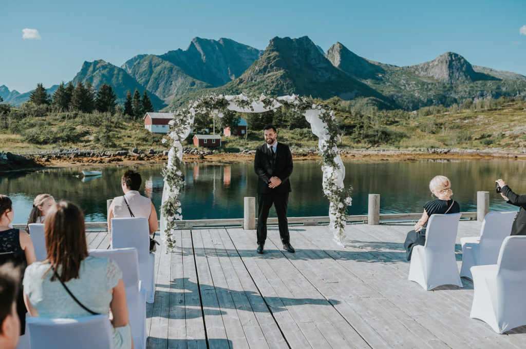 Outdoor summer wedding ceremony at Nyvågar rorbu hotel in Kabelvåg Lofoten. The groom is waiting for his bride