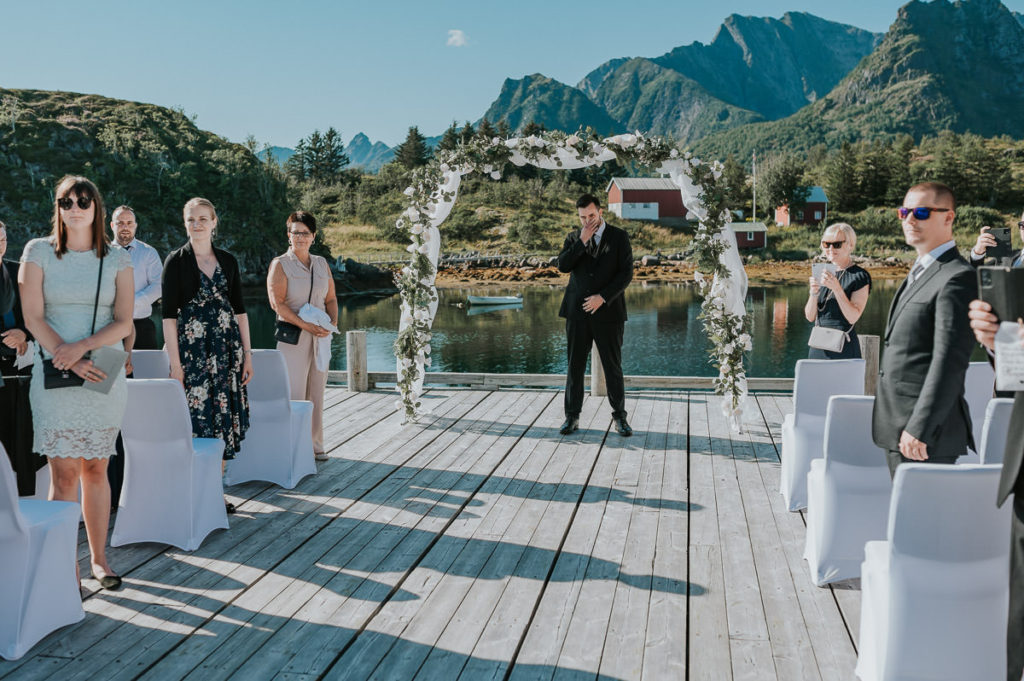 Outdoor summer wedding ceremony at Nyvågar rorbu hotel in Kabelvåg Lofoten. The groom is waiting for his bride