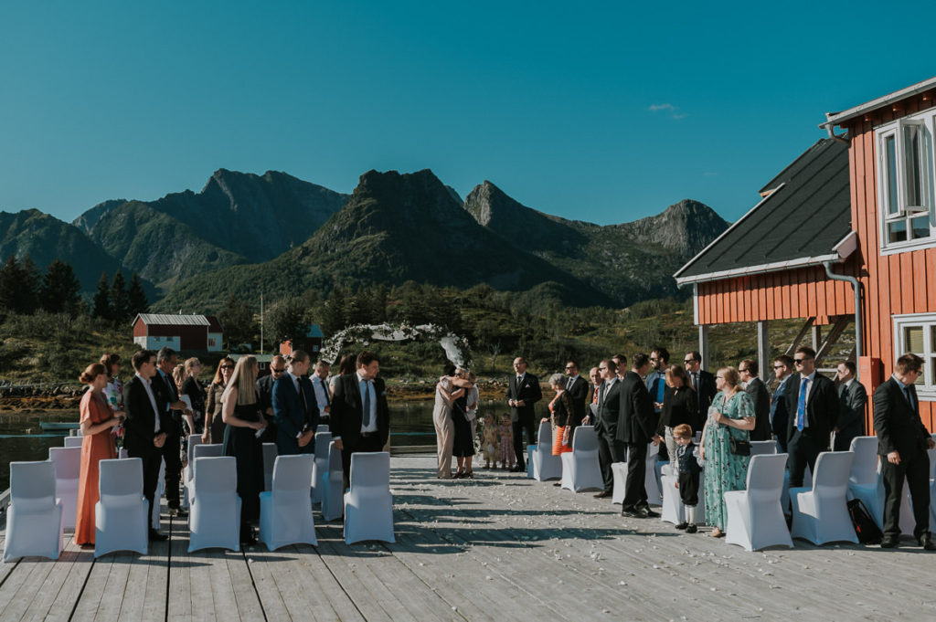 Bride and groom walking hand in hand after their outdoor adventure wedding ceremony in Lofoten, Norway. The guests are throwing flower petals on them and everybody is cheering