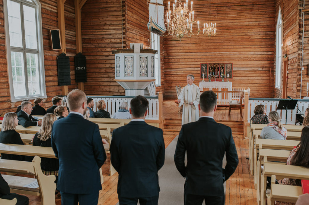The priest speaking to the wedding guests in Hillesøy church in Tromsø before the wedding ceremony - by Tromsø wedding photographer TS Foto Design