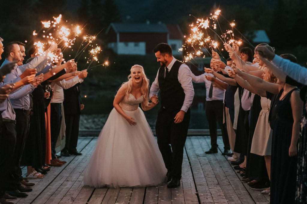 Sparkler exit on a wedding day in Lofoten Norway. Bride and groom are dancing trherugh the exit and laughing